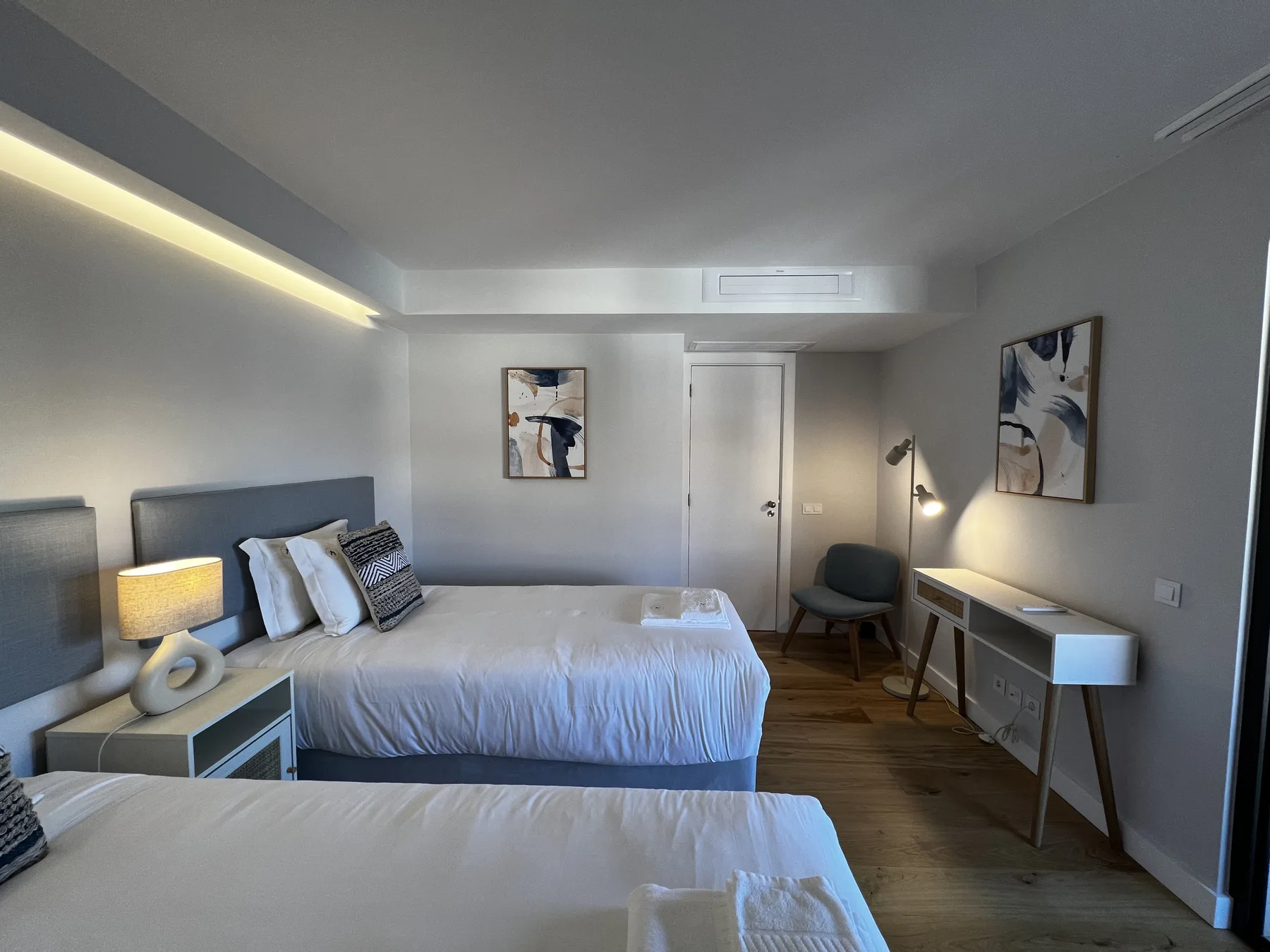 A bedroom with two beds, a desk, and wall art.
