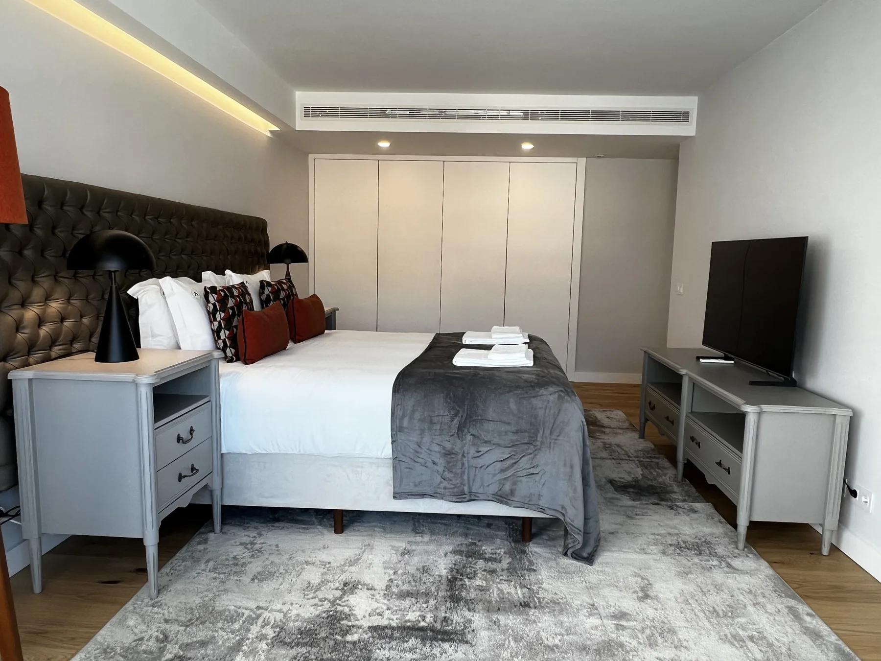 A bedroom with a bed, bedside tables, and a television.