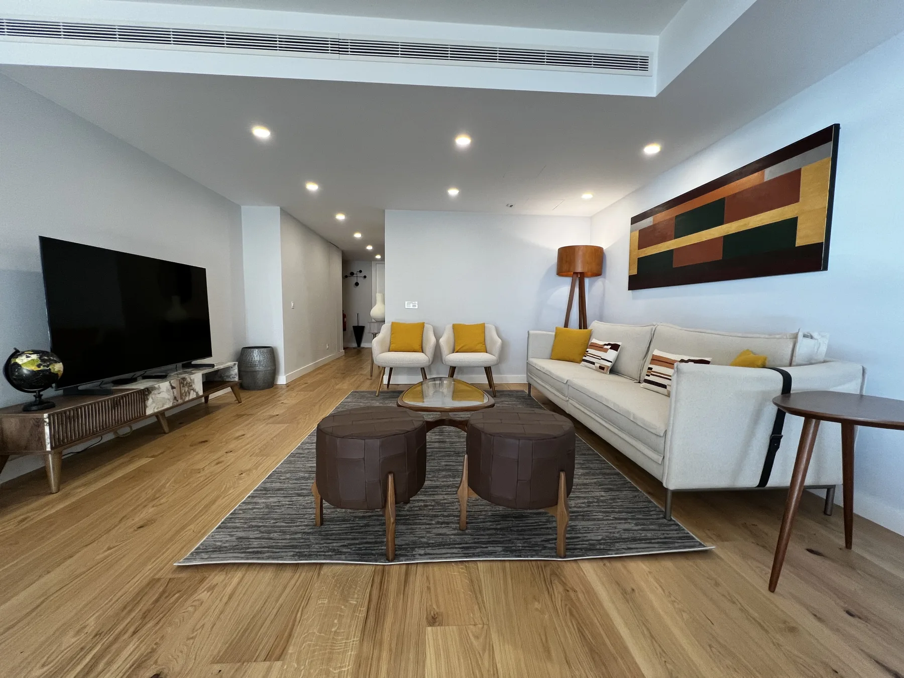 A modern living room with seating arranged around a coffee table and television.