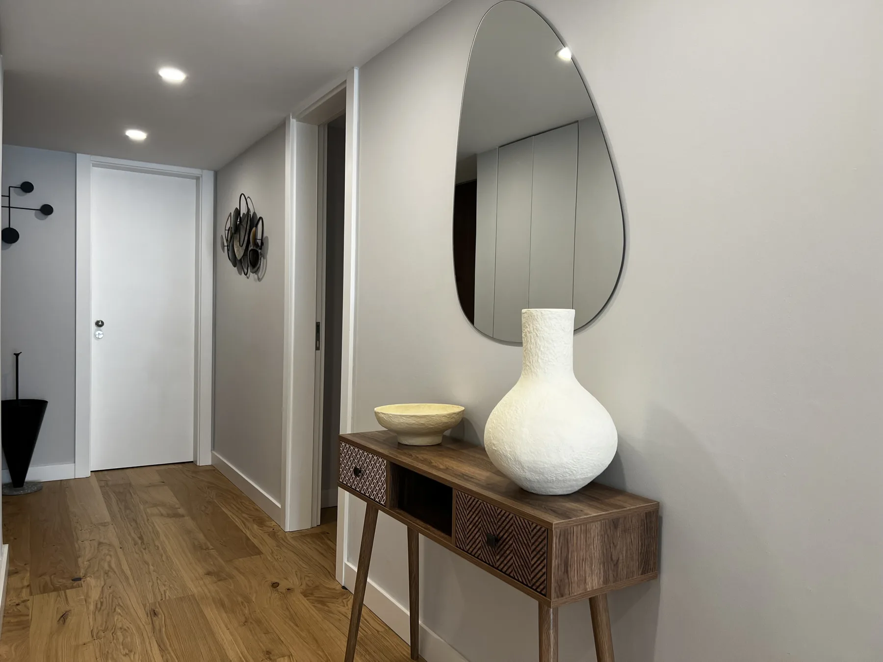An interior hallway with a wooden console table, decorative bowl, and mirror.