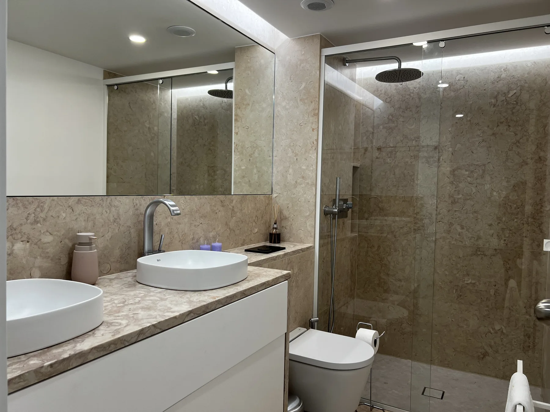 A modern bathroom with a sink, mirror, and glass-enclosed shower.
