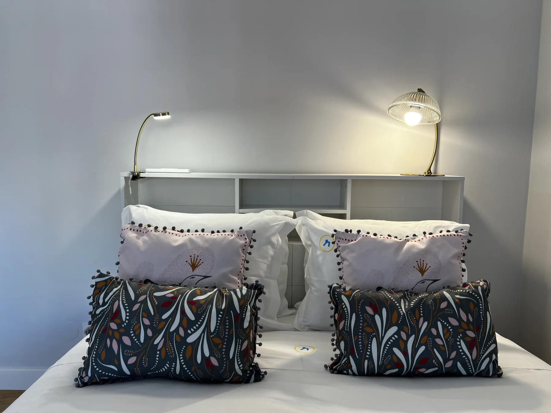 A bedroom with a neatly made bed and patterned decorative pillows.