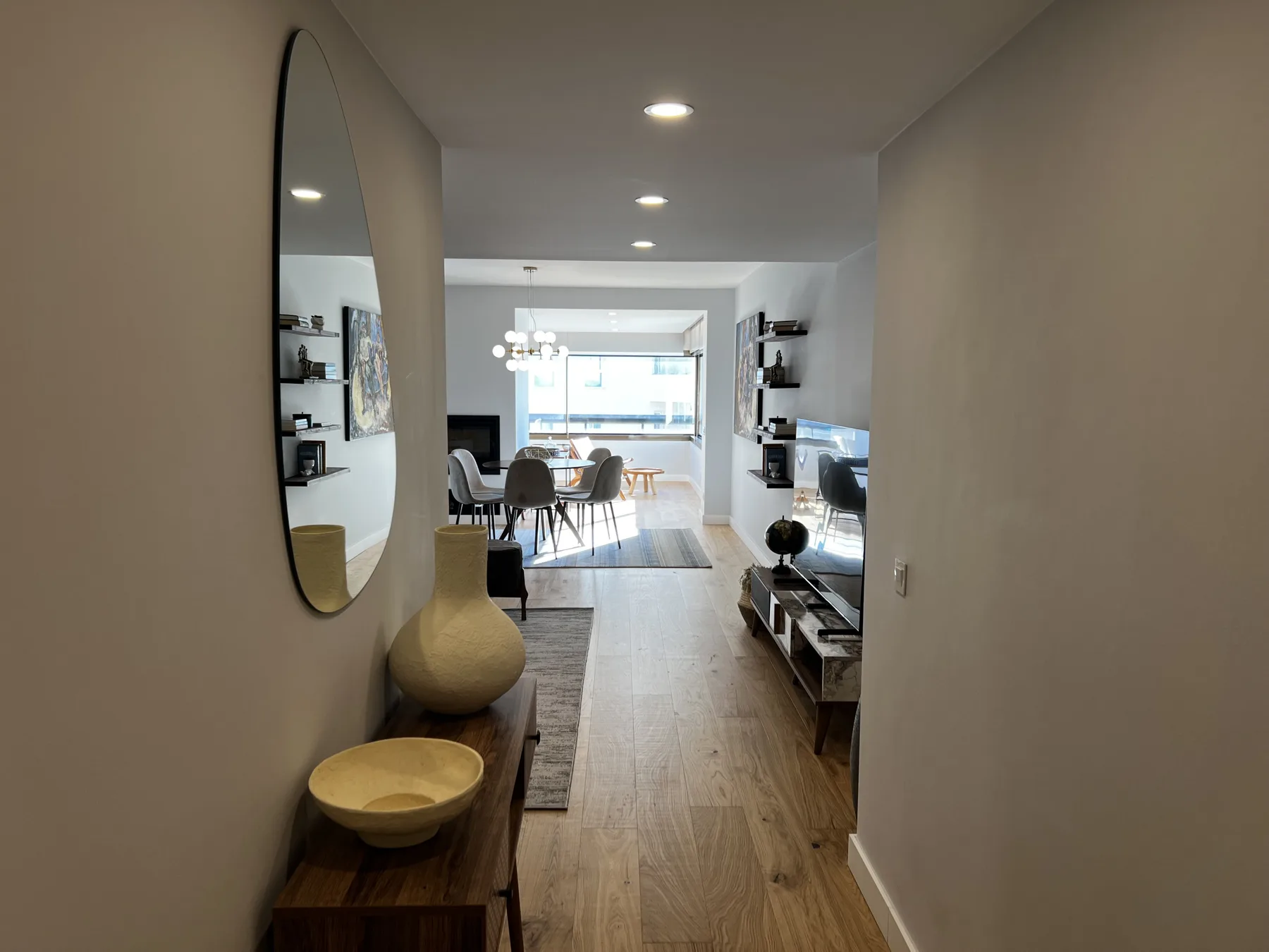 A hallway opens onto a living and dining area with a television and table.