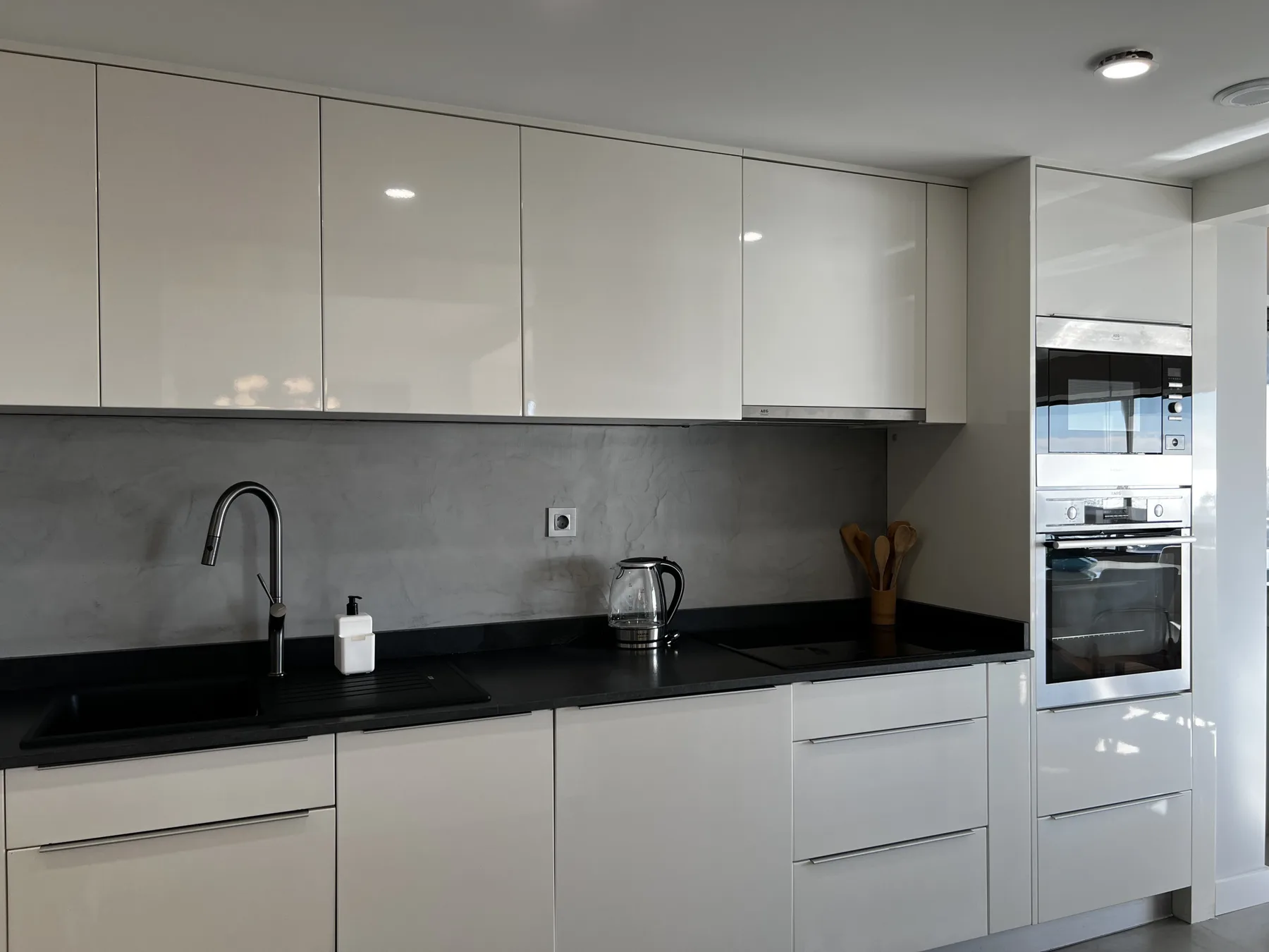 A modern kitchen with white cabinets, a dark countertop, and built-in appliances.