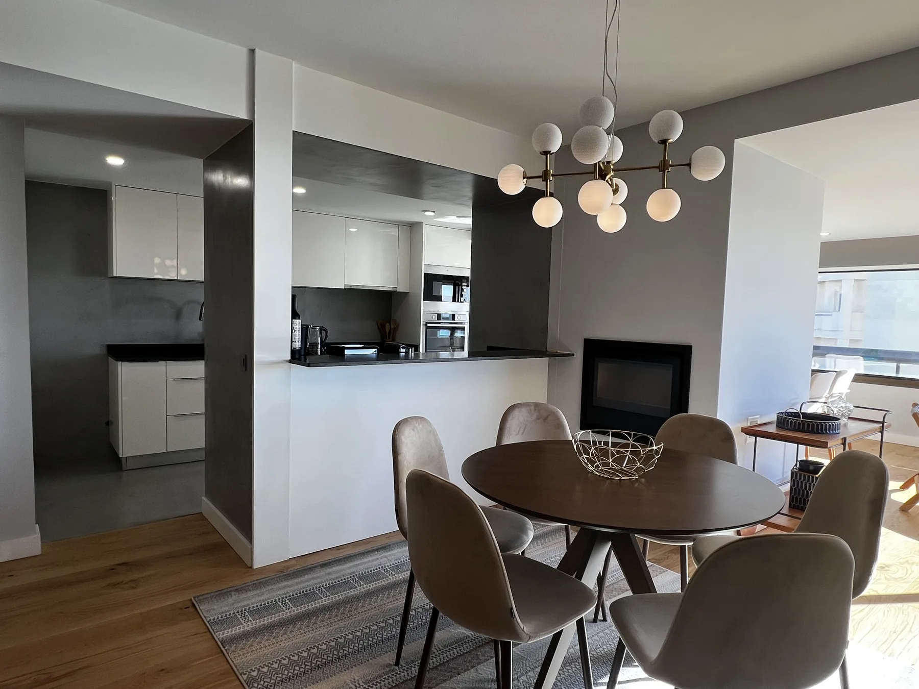 A dining area with a round table and seating beside an open kitchen and living area.