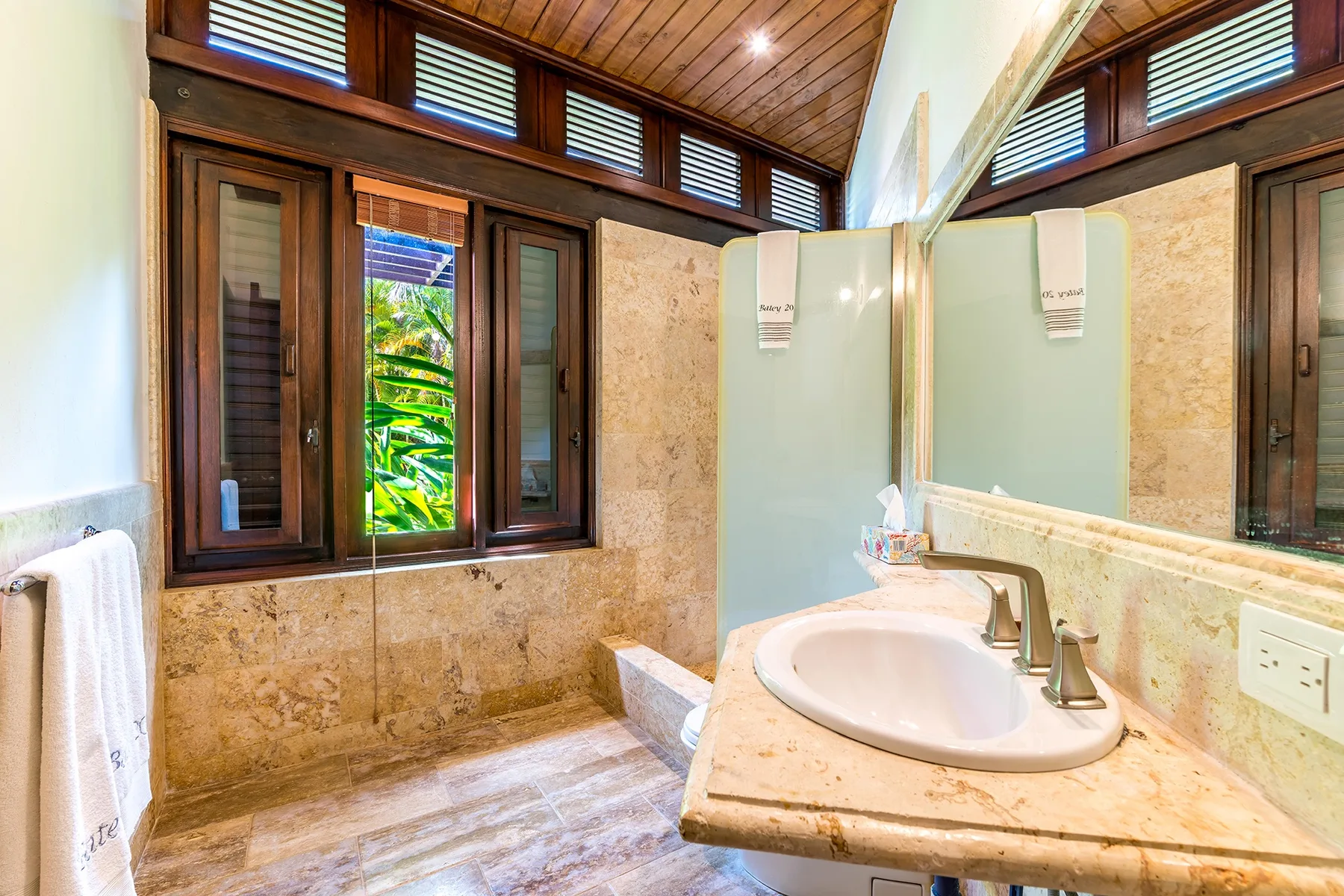Un lavabo de baño está junto a una ventana y paredes de piedra.