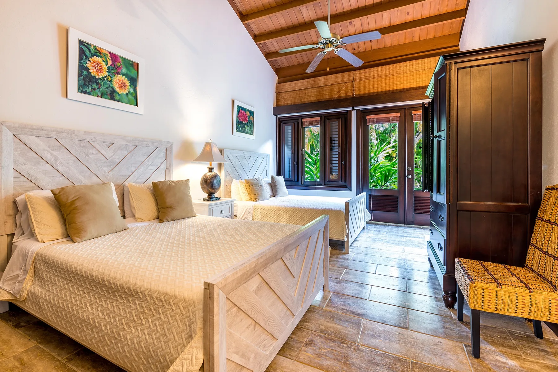 Un dormitorio con dos camas, muebles de madera oscura y ventanas con vistas a la vegetación.