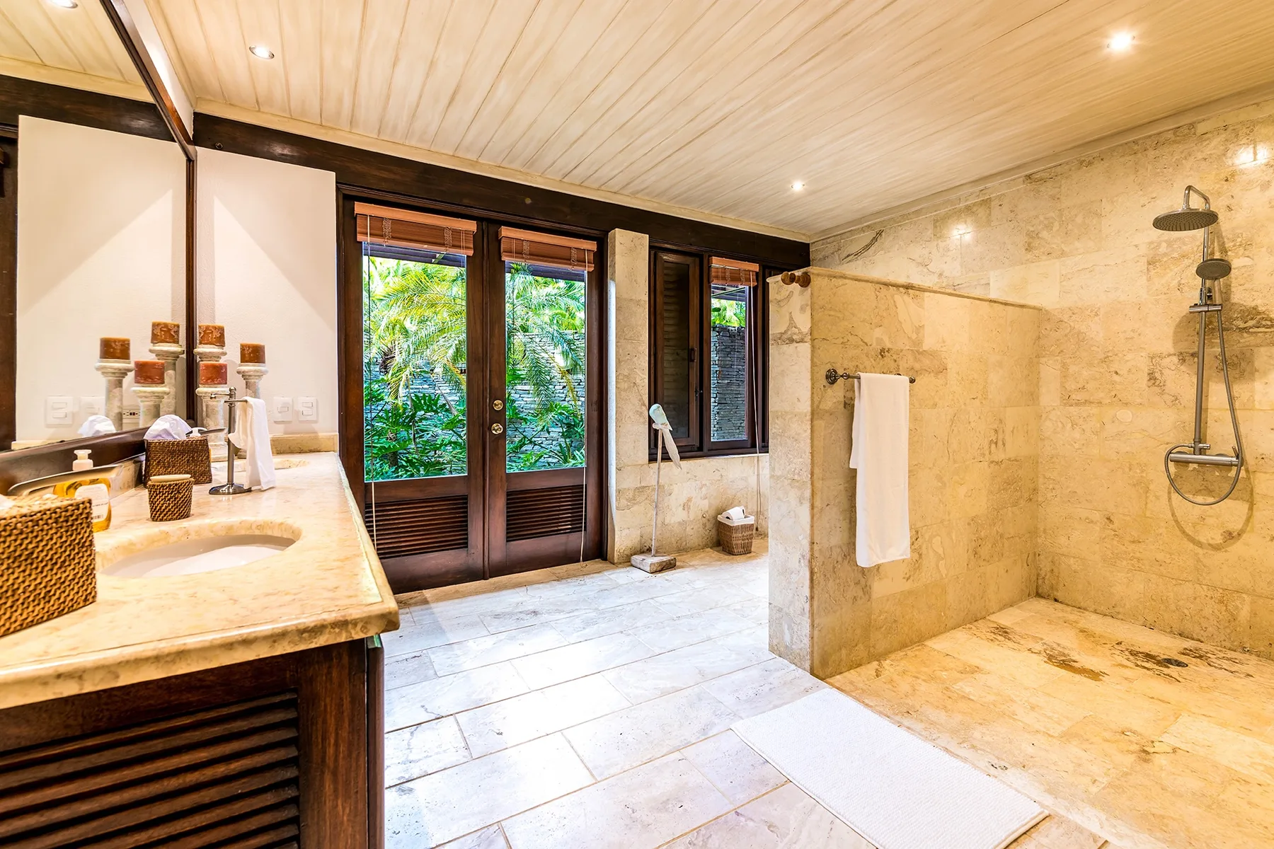 Un baño amplio con tocador, puertas de vidrio y una zona de ducha abierta.
