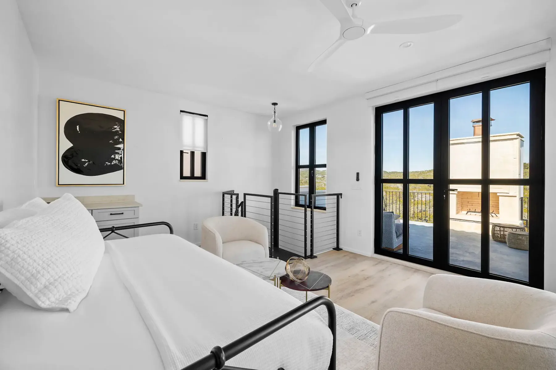 A bright bedroom with a white bed and large glass doors opening onto a terrace.