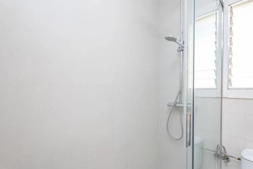 A bright bathroom with a glass shower and a window.