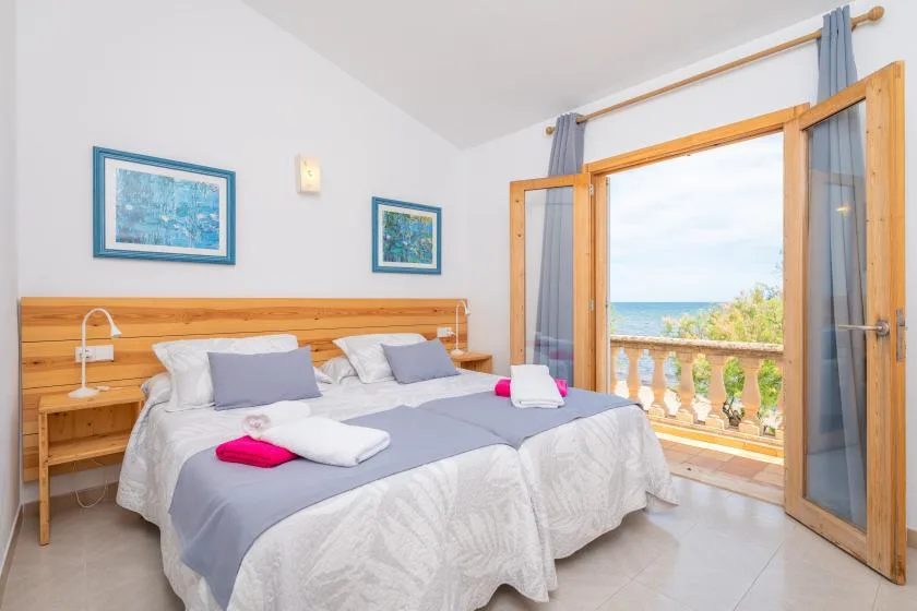 A bedroom with two beds and an open doorway overlooking the sea.