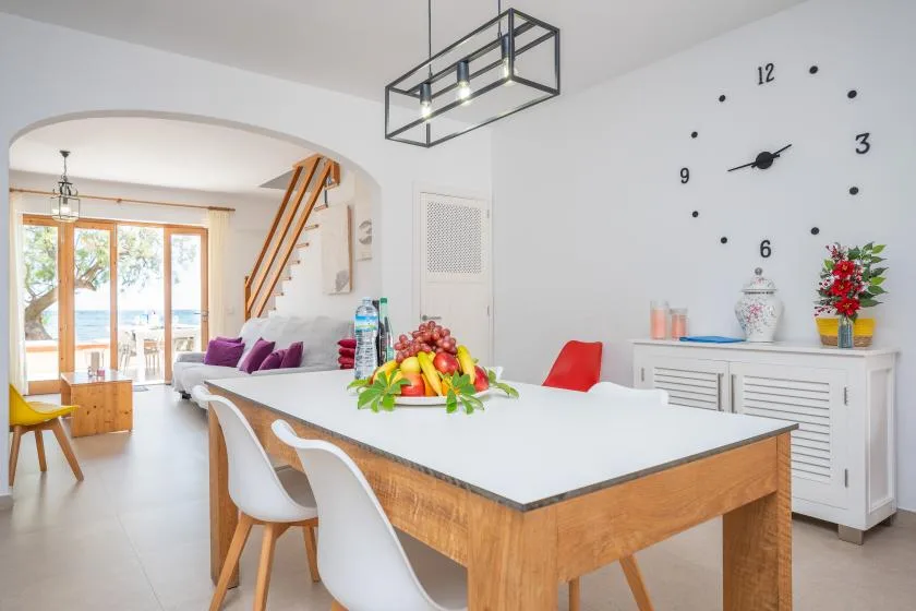 A bright dining area with a long table and glass doors opening onto a patio.