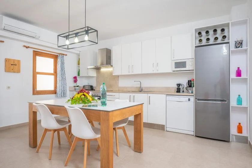 A bright kitchen and dining area with a wooden table and white cabinetry.