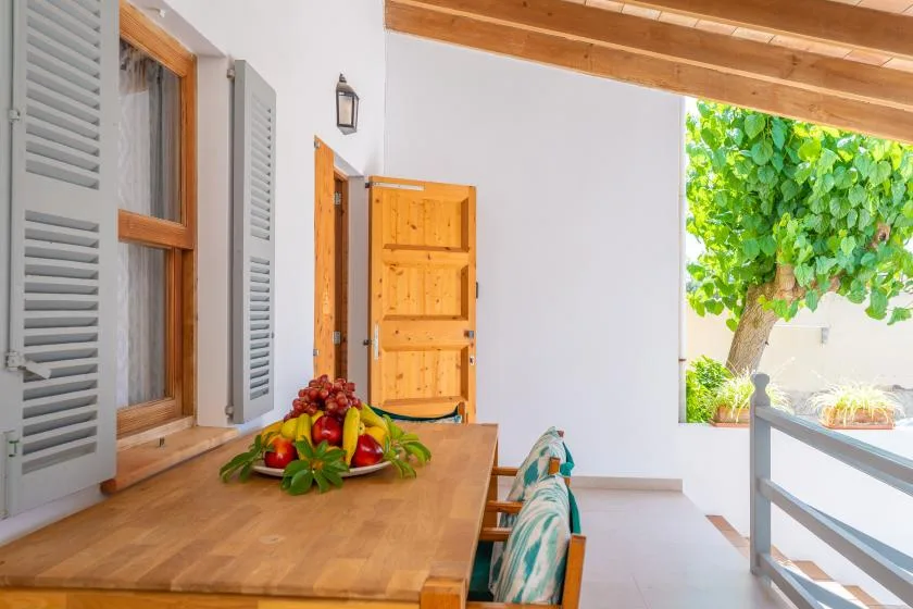 A covered patio with a wooden table and an open doorway.