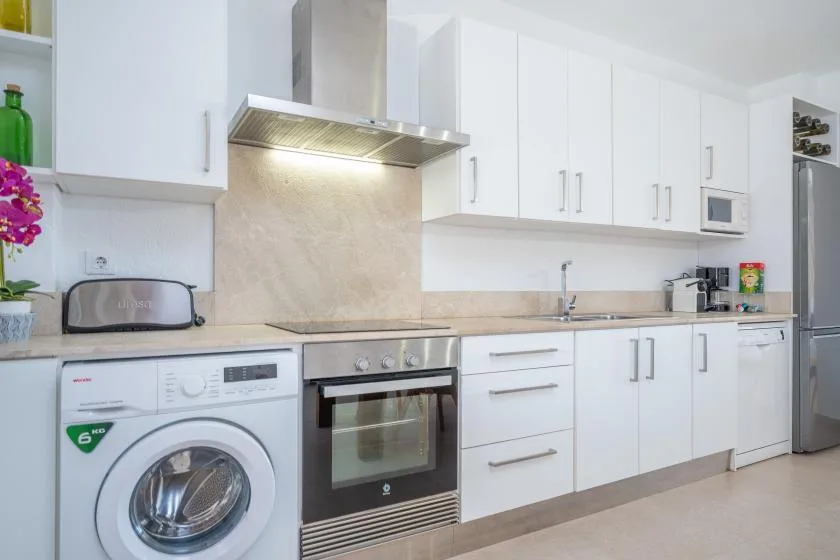 A bright kitchen with white cabinets, a countertop, and built-in appliances.