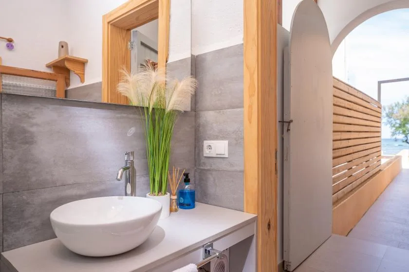 A bathroom vanity with a white vessel sink and a doorway opening onto a balcony.