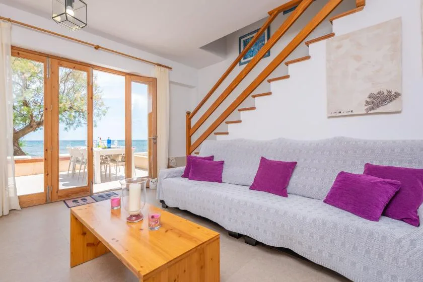 A living room with a long sofa beneath a wooden staircase.