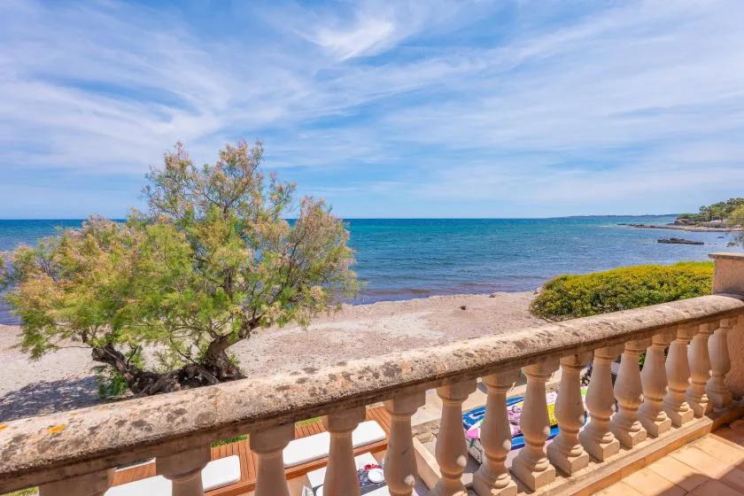 A seaside terrace overlooks the blue water and a sandy shoreline.