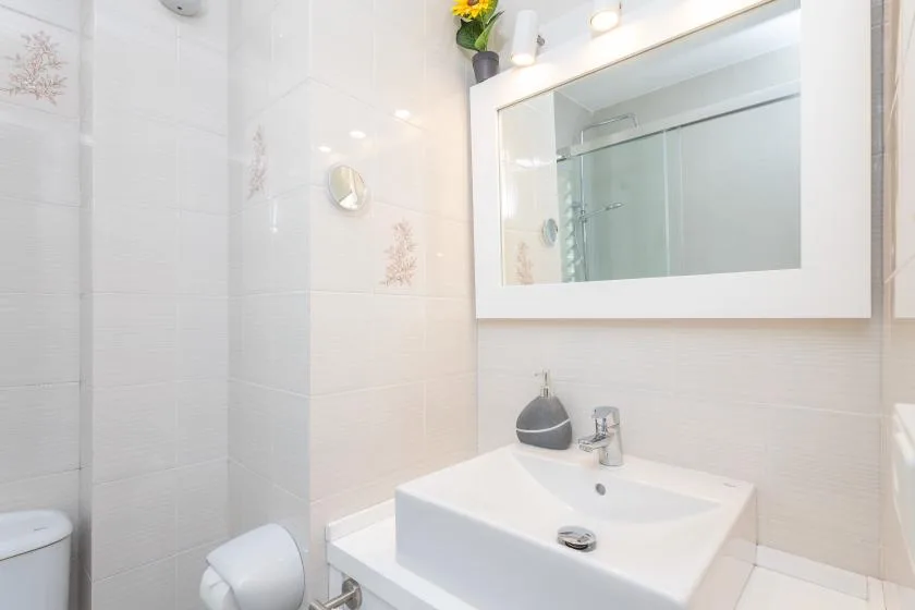 A bright bathroom with a white sink beneath a large mirrored cabinet.