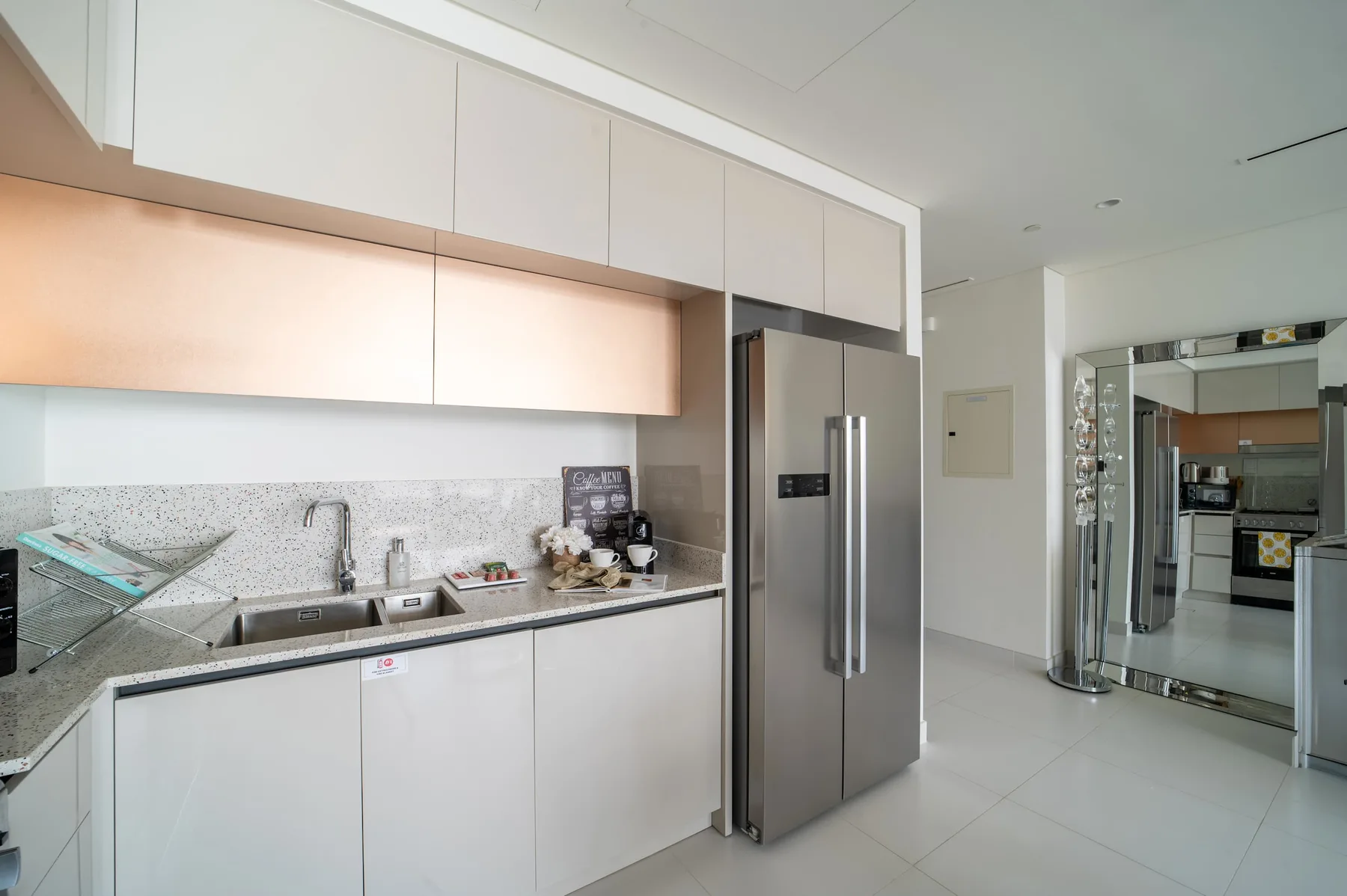 Una cocina moderna con gabinetes blancos, una encimera y un refrigerador de acero inoxidable.