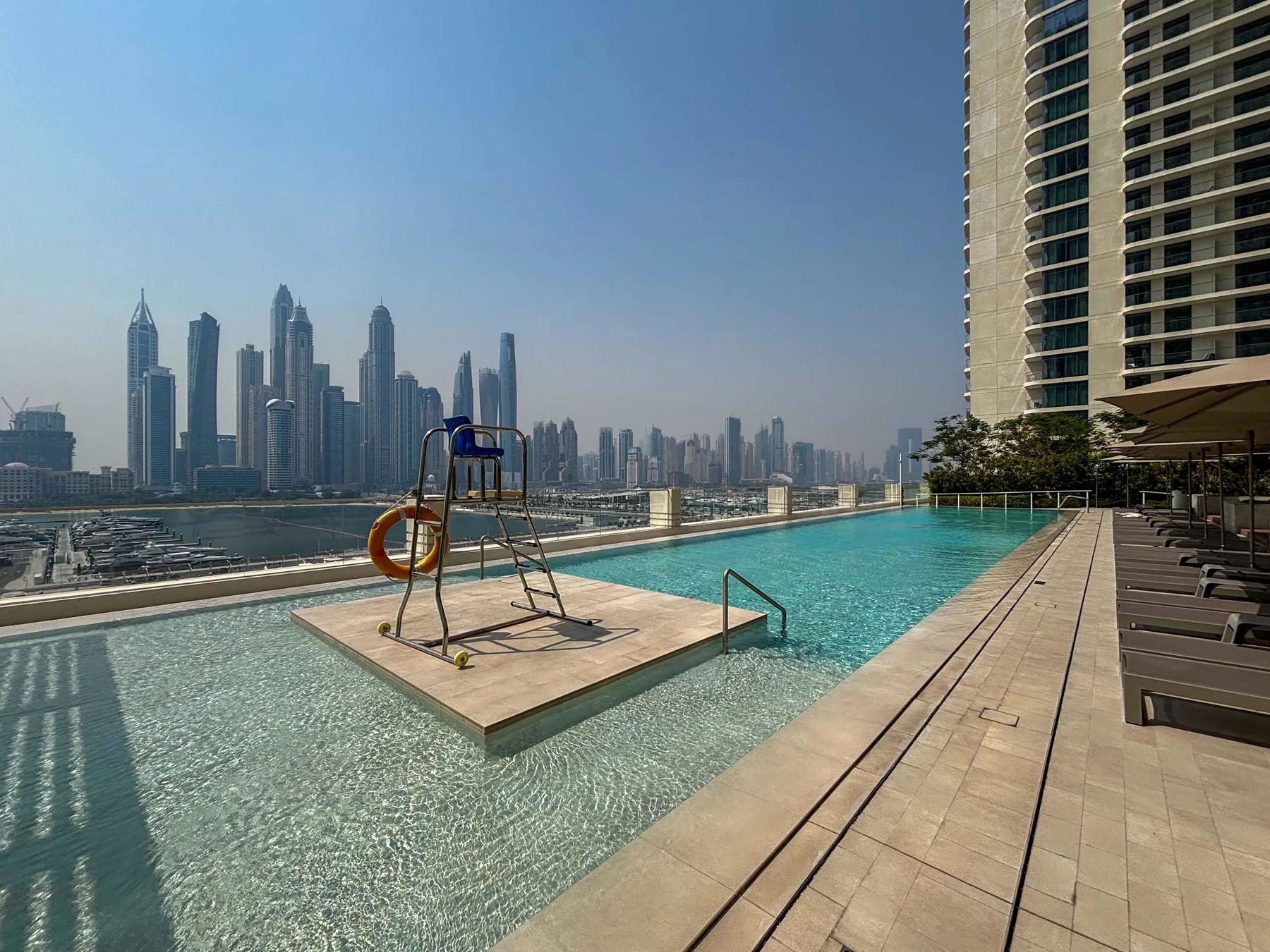 Una piscina en la azotea ofrece vistas al horizonte de la ciudad, con una silla de salvavidas sobre una plataforma.