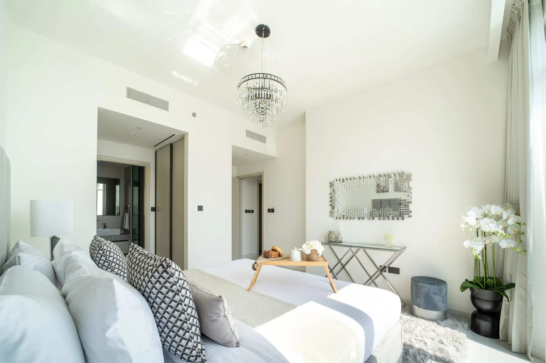 Un dormitorio luminoso con una cama, una mesa pequeña y una lámpara de araña.