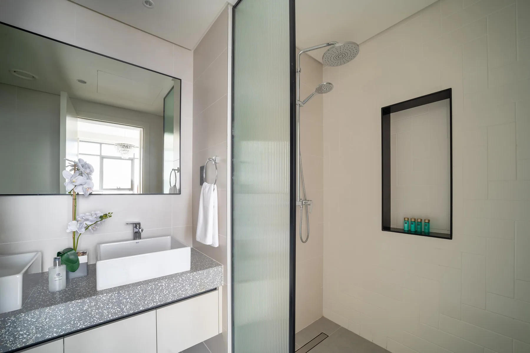 Un baño luminoso con un lavabo doble y una ducha con paneles de vidrio.