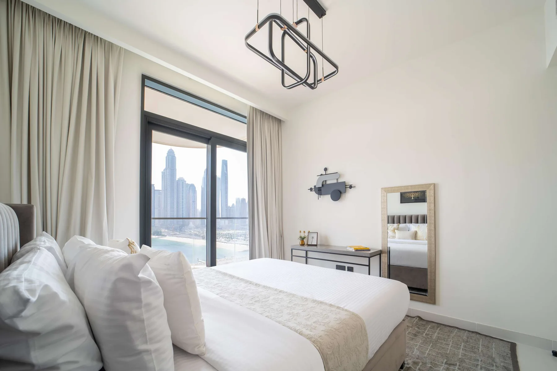 Un dormitorio luminoso con una cama grande y vistas a la ciudad a través de puertas de vidrio.