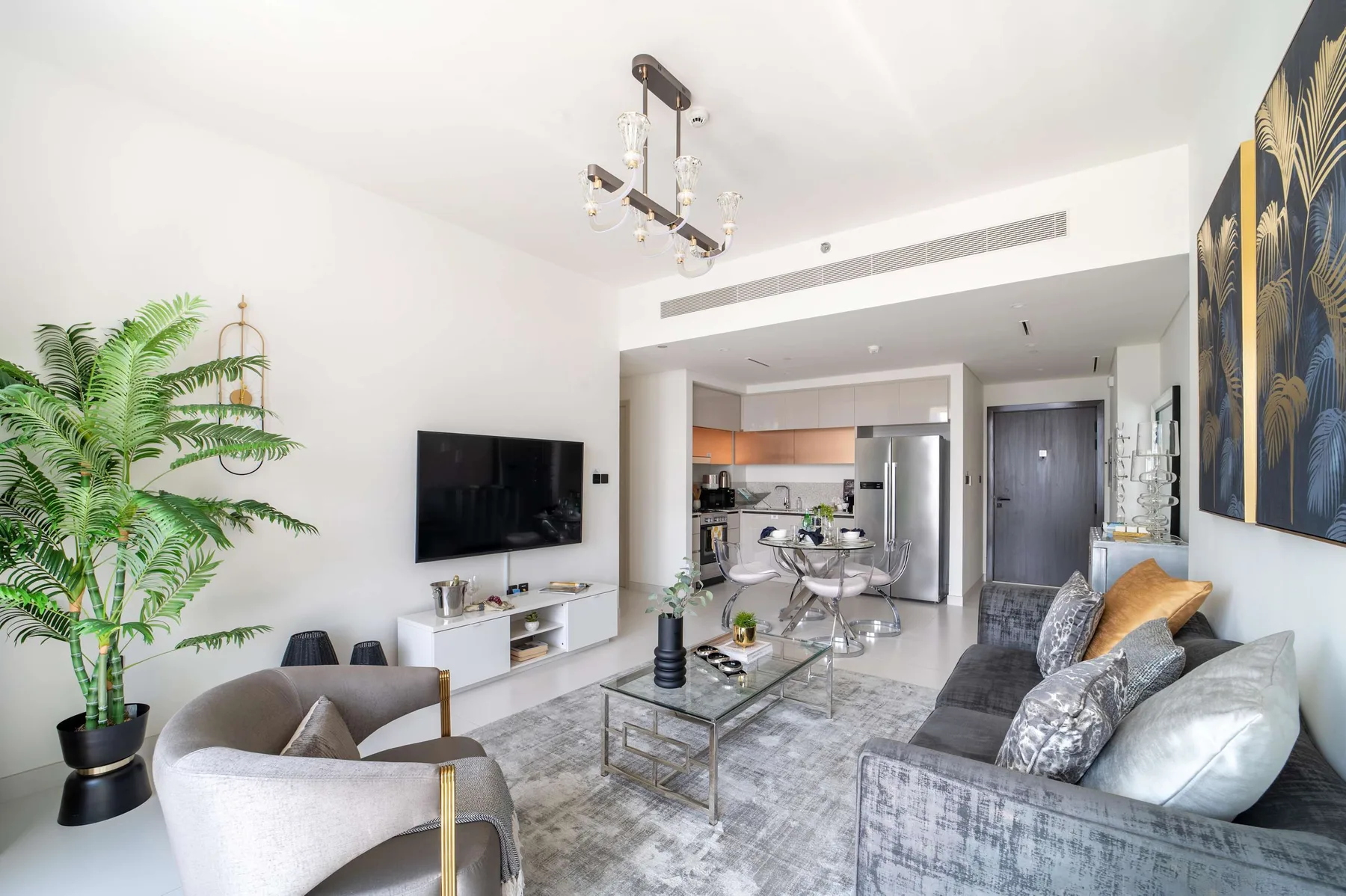 Una sala de estar moderna con asientos, un televisor y una cocina abierta.