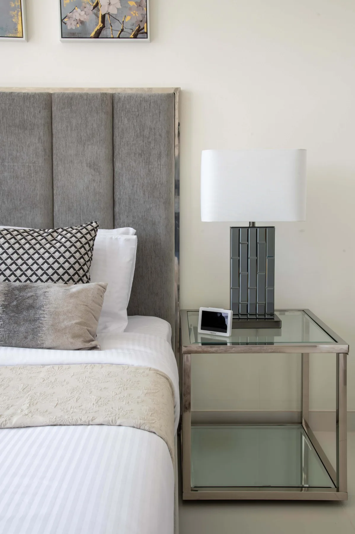 Un dormitorio con una cama bien tendida y una mesita de vidrio.
