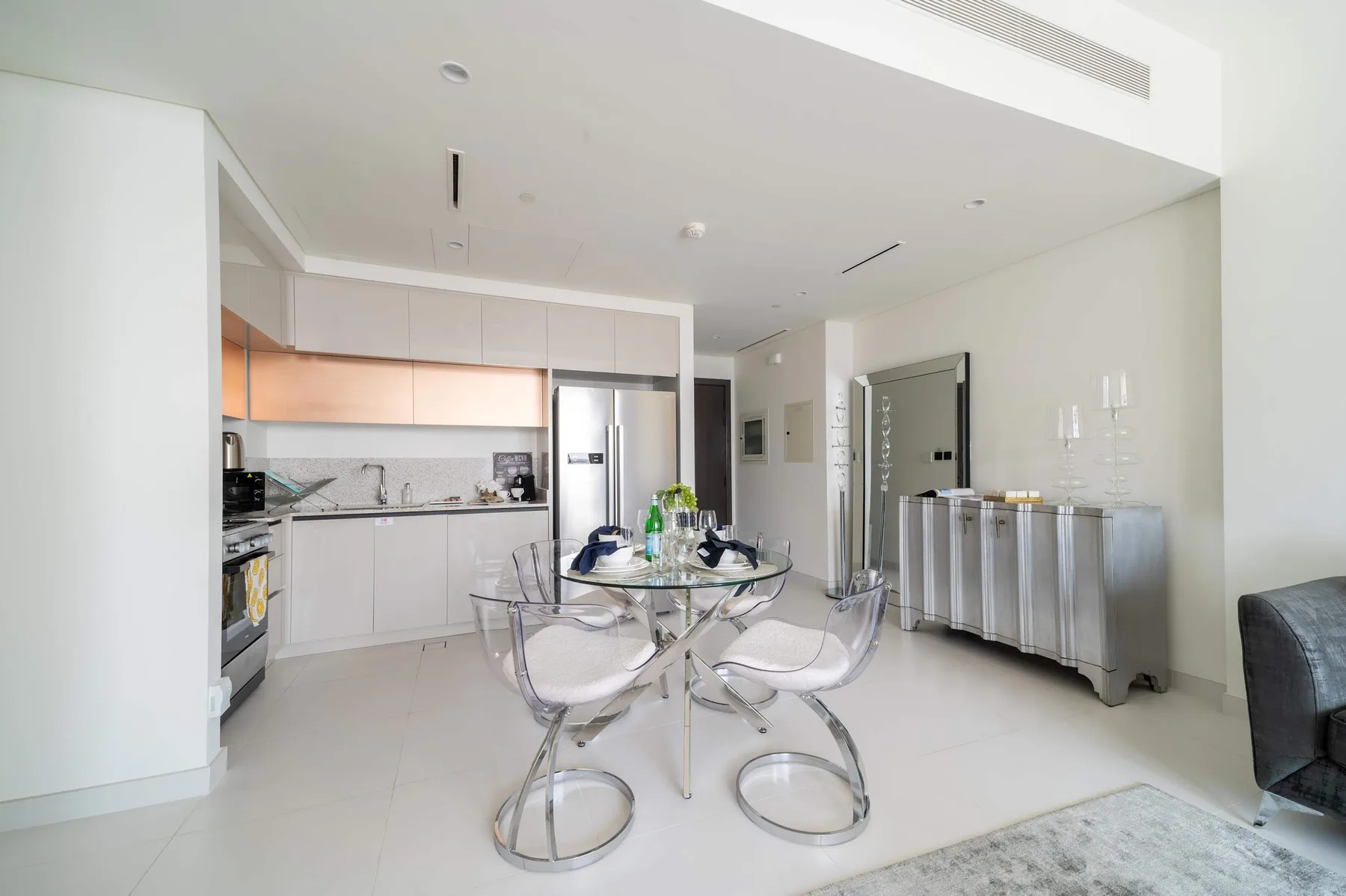 Un comedor luminoso con una mesa de vidrio está junto a una cocina moderna.