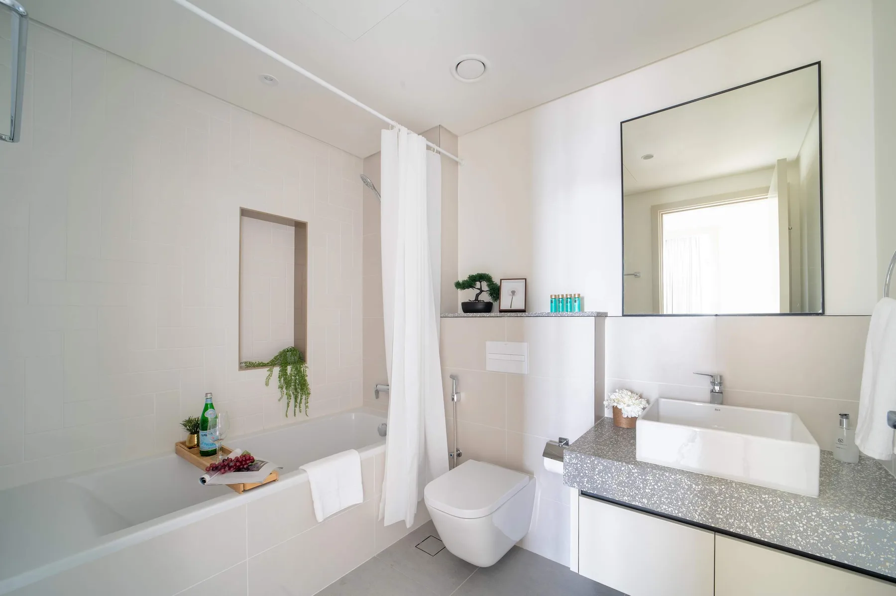 Un baño luminoso con bañera, cortina de ducha, inodoro y lavabo.