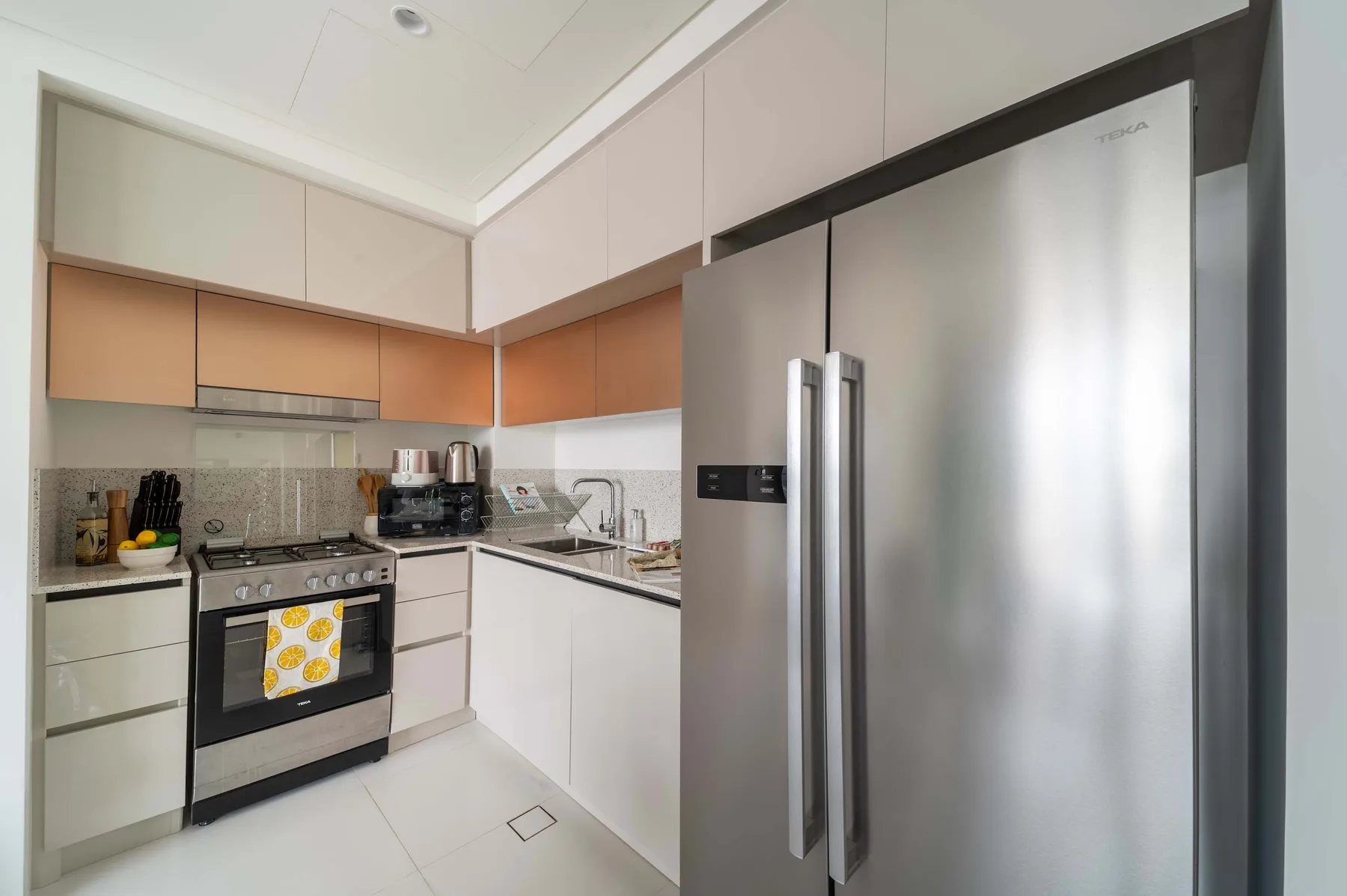 Una cocina moderna con gabinetes claros, una estufa y un refrigerador de acero inoxidable.