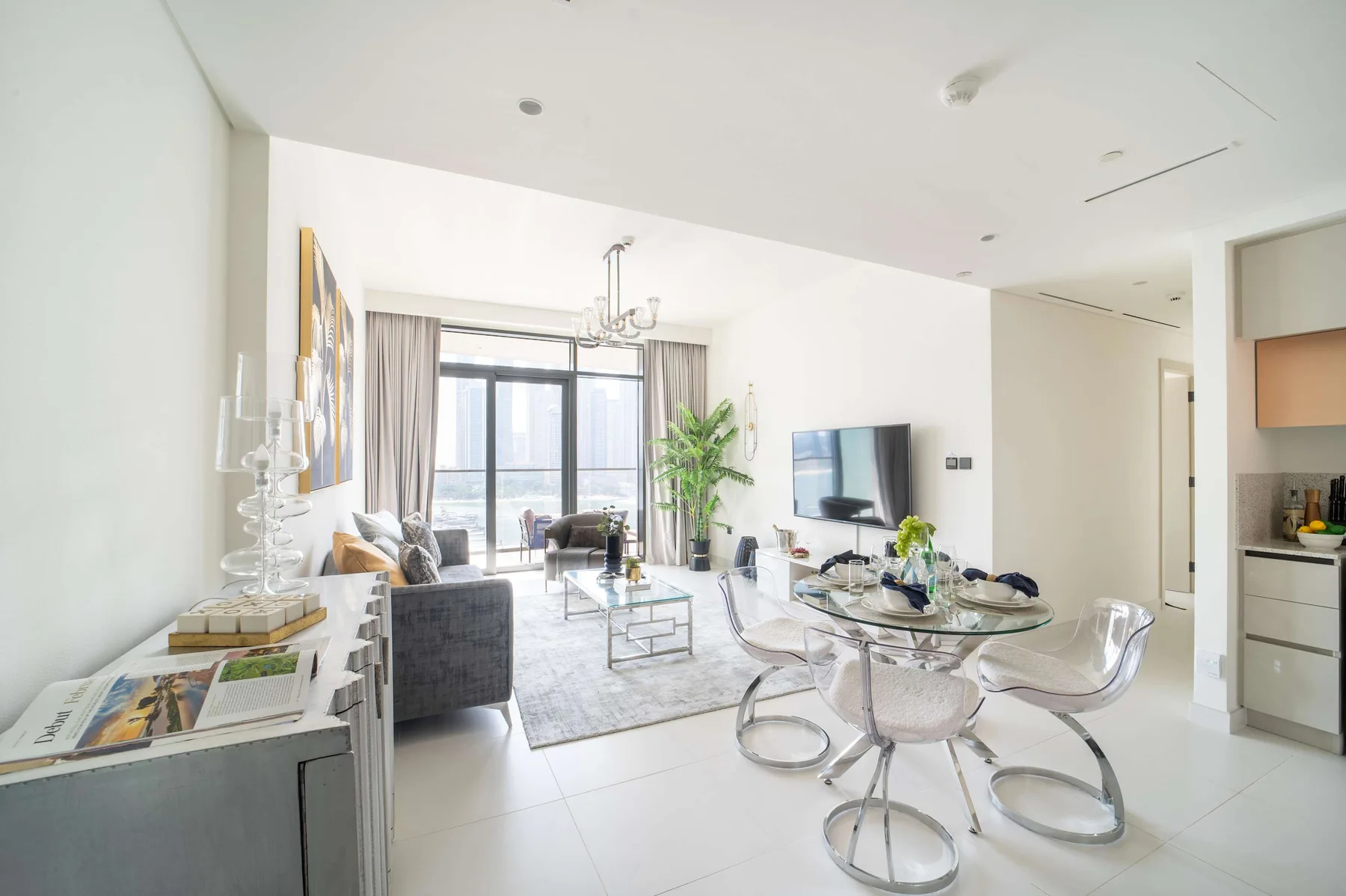 Una luminosa sala de estar y comedor con televisor y mesa de vidrio.
