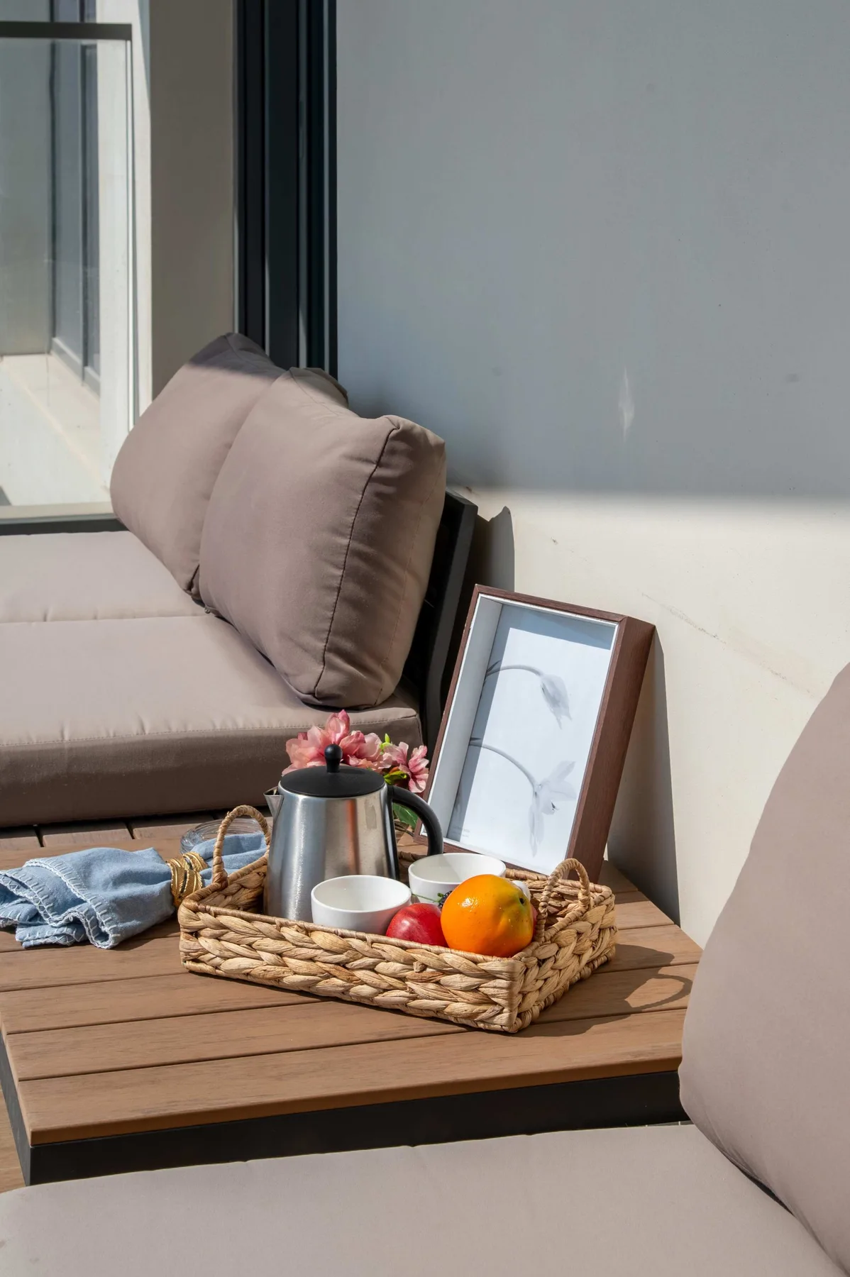 Una zona de asientos al aire libre con una mesa de madera y una cesta de fruta.