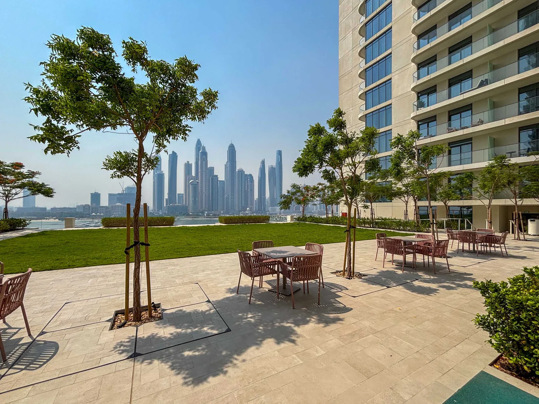 Una terraza exterior con asientos mira hacia un horizonte junto al agua, junto a un edificio moderno.