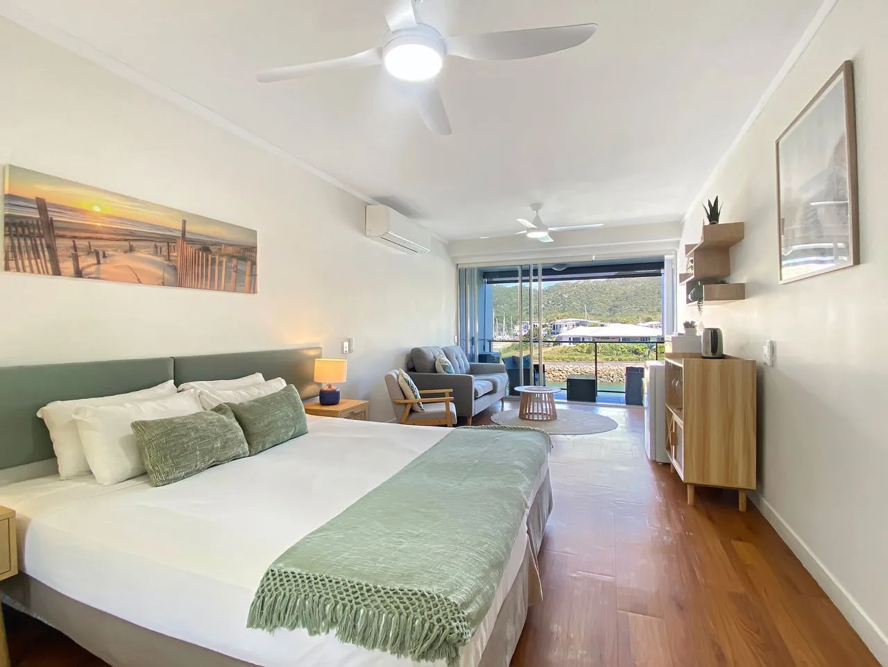 Un dormitorio luminoso con una cama grande y una zona de estar junto a la ventana.
