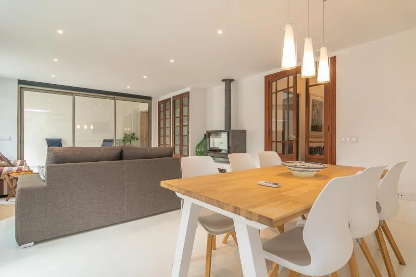 Una sala de estar y comedor diáfana con una mesa de madera y asientos.