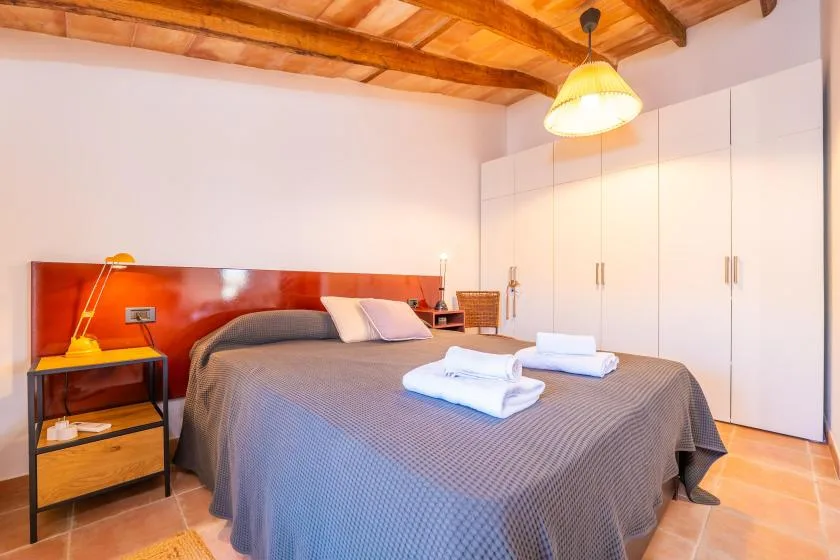 Un dormitorio con una cama doble, toallas dobladas y armarios empotrados.