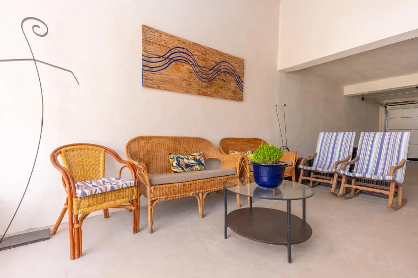 Una luminosa zona de estar interior tiene muebles de mimbre y cojines a rayas.