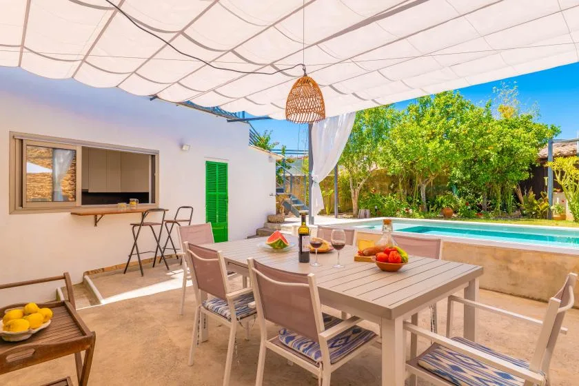 Un patio comedor al aire libre con una mesa bajo un toldo de tela.