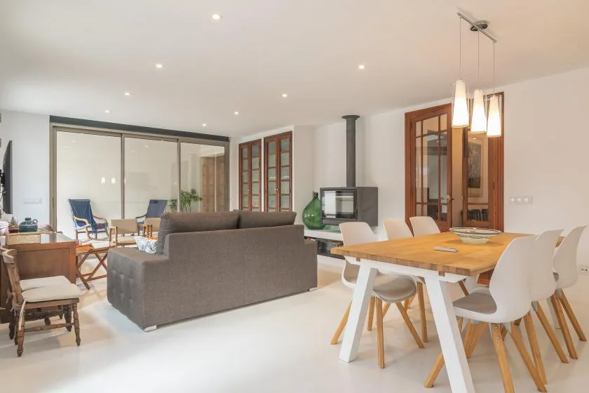Una zona abierta de sala y comedor con un sofá gris y una mesa de comedor de madera.