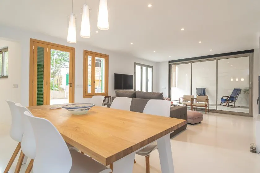 Un luminoso espacio abierto de comedor y sala de estar con mesa de madera y ventanas amplias.