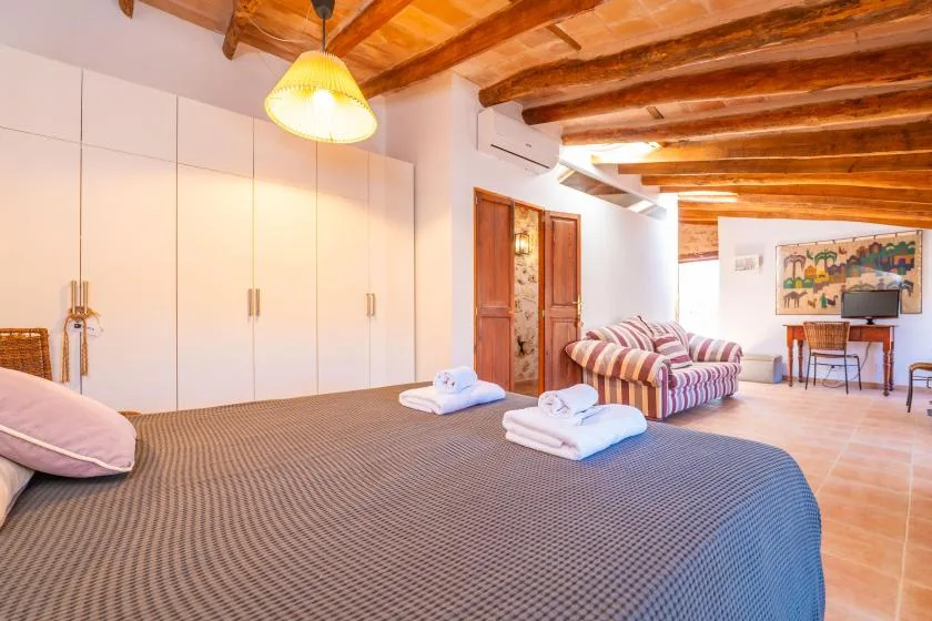 Un dormitorio con una cama grande, armarios empotrados y una zona de estar al fondo.