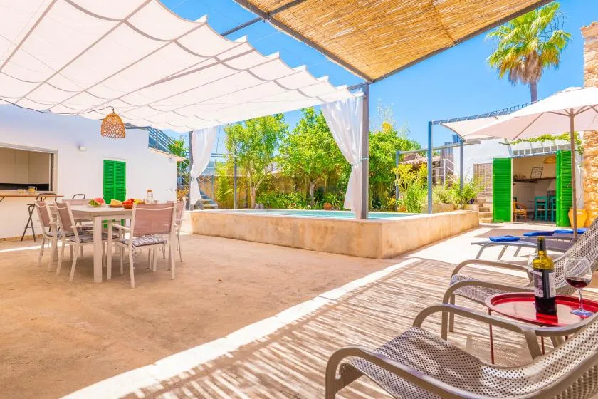 Patio al aire libre con mesa de comedor, asientos y zonas de sombra.