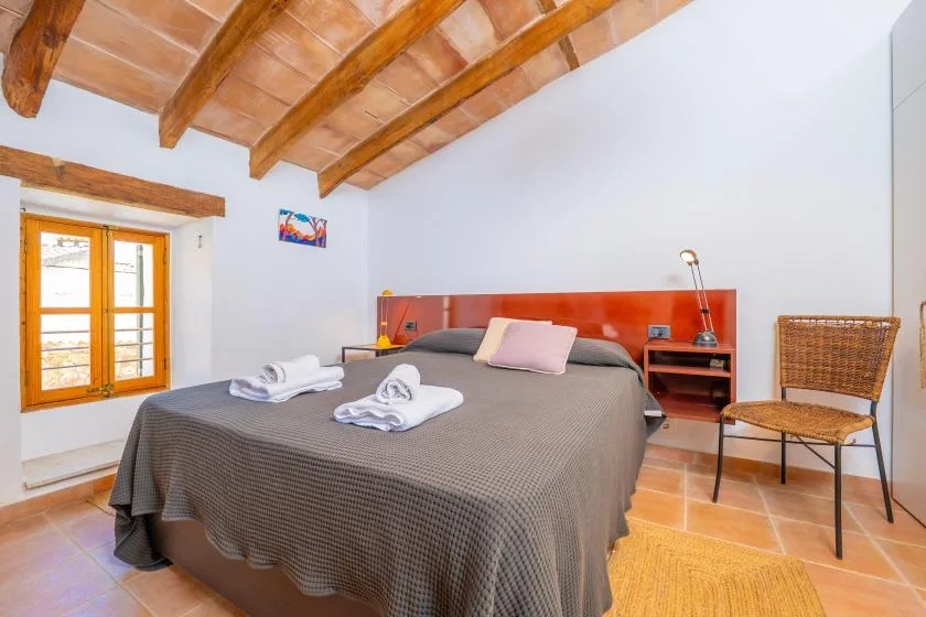Un dormitorio con una cama doble bajo vigas de madera expuestas.