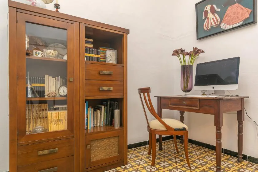 Una zona de estudio con escritorio de madera, ordenador y estantería.
