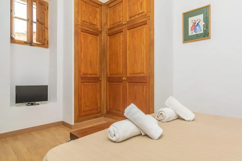 Un dormitorio con armarios empotrados de madera y toallas enrolladas sobre la cama.