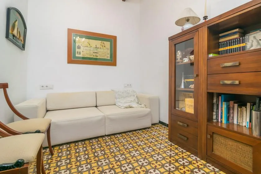 Una sala de estar con asientos claros y una estantería de madera.