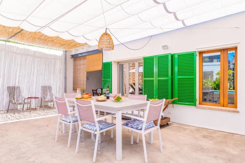 Una zona de comedor exterior cubierta con una mesa y contraventanas verdes.